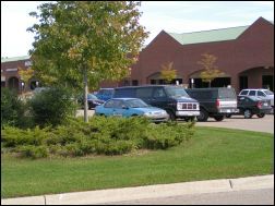 Parked cars in a parking lot next to green space with trees